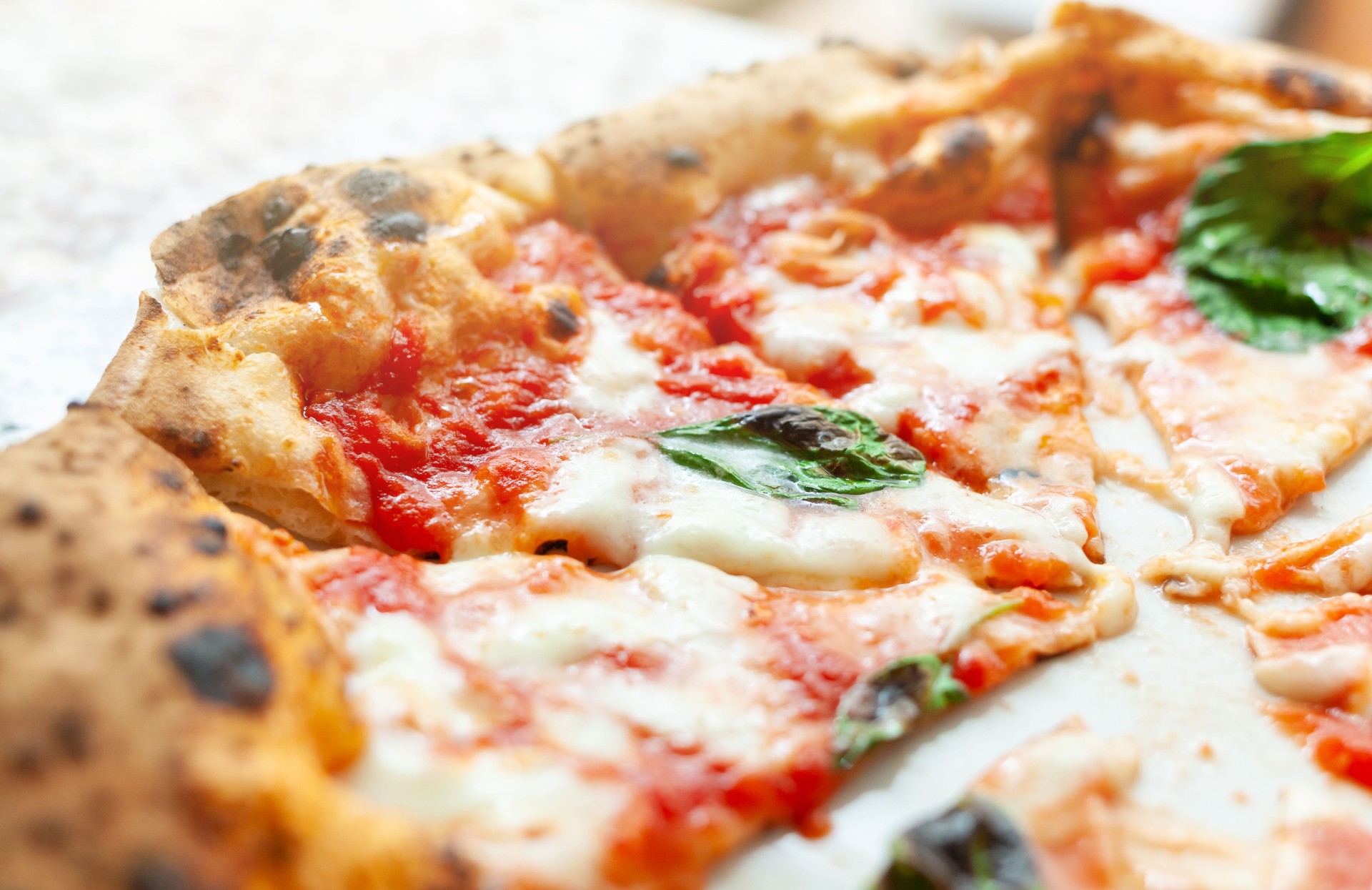 Delicious Neapolitan pizza with melted mozzarella, tomato sauce and basil leaves